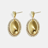Statement earrings with an oval charm surrounded by stones